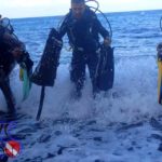 Scuba divers who are environmental activists coming to the beach after doing a Project Aware Dive Against Debris